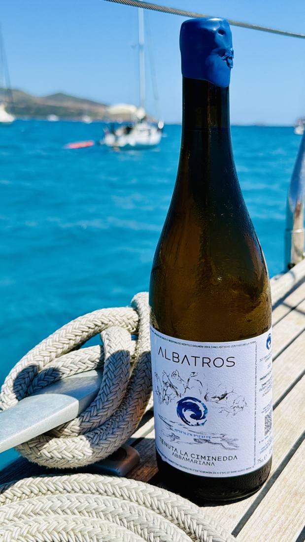 Una bottiglia di Albatros sul ponte di una barca a vela, con il mare dietro